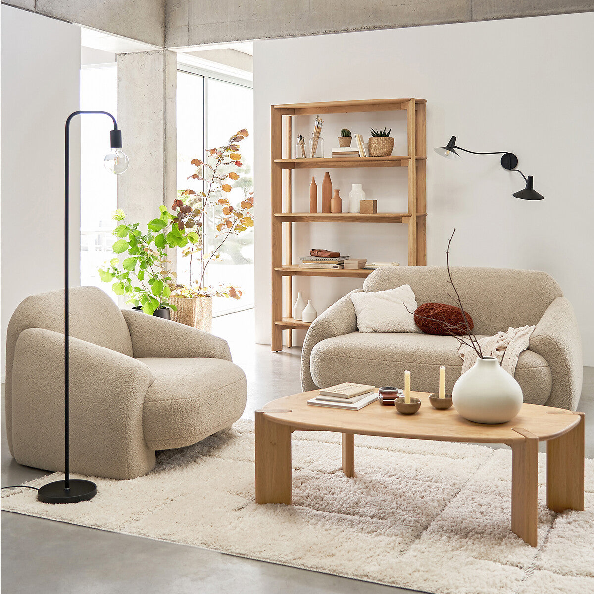 Canapé en bouclette beige dans un salon lumineux avec fauteuil assorti et table basse en bois